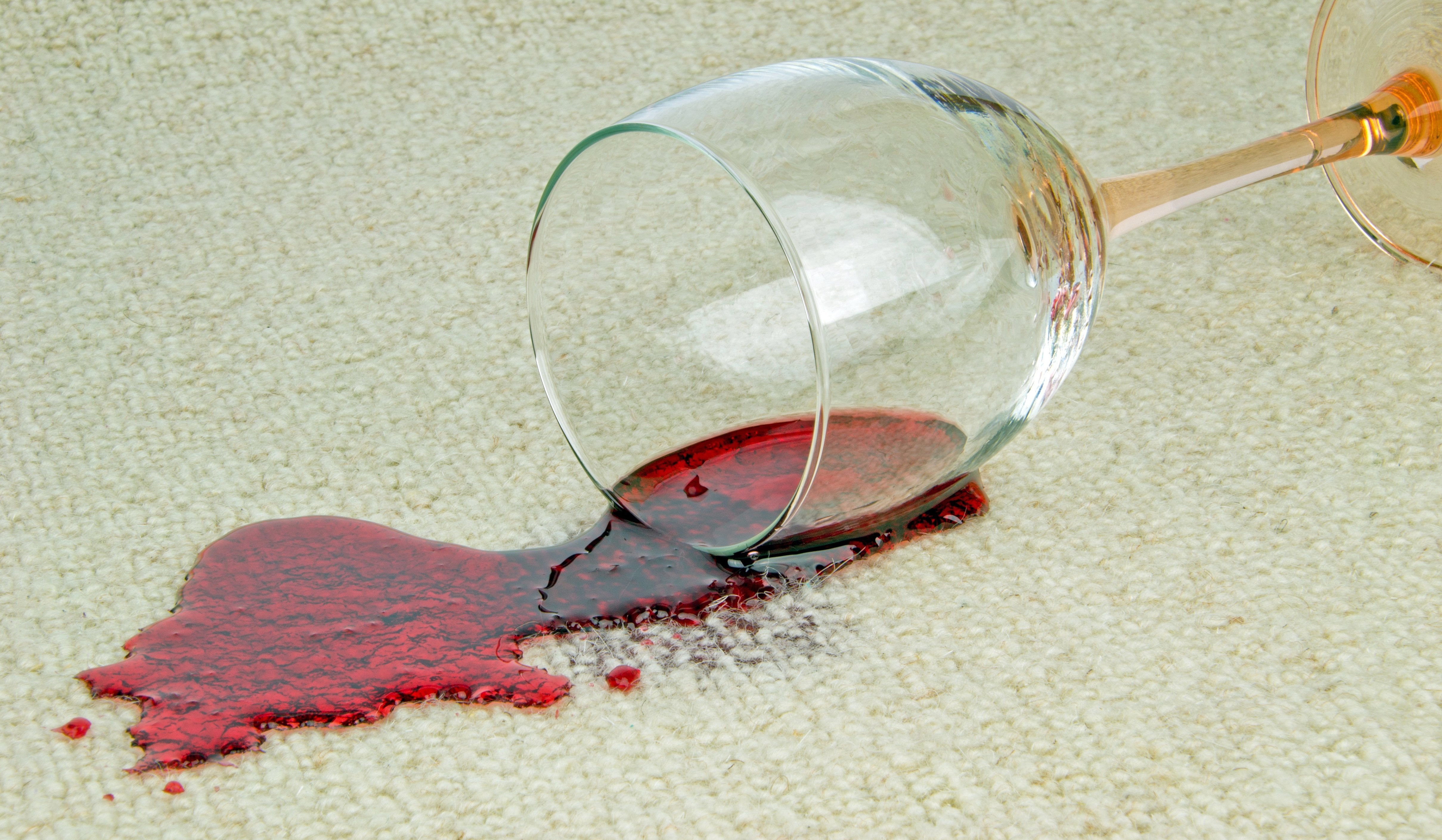 Разлитое вино на белом ковре