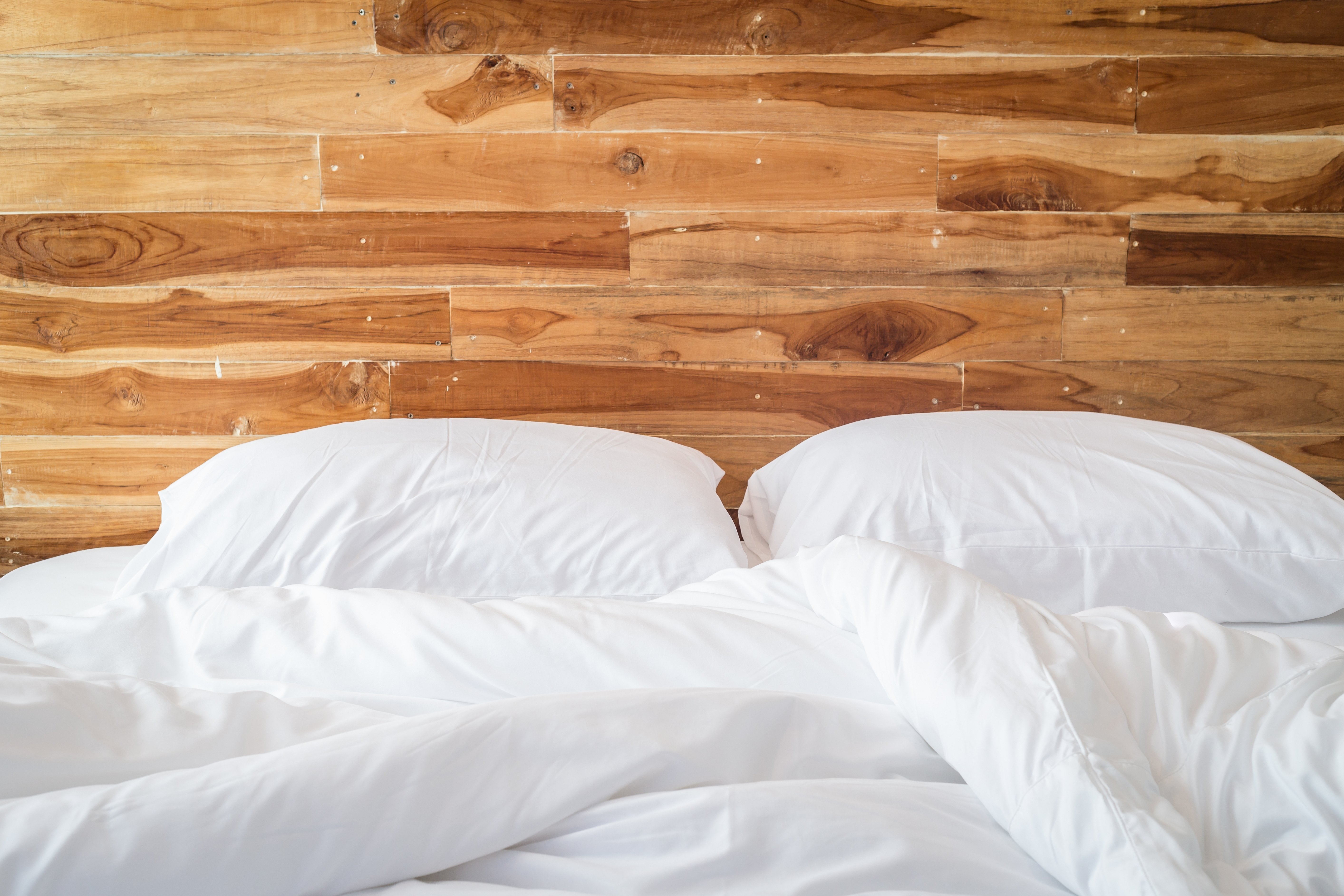 Кровать на фоне деревянной стены